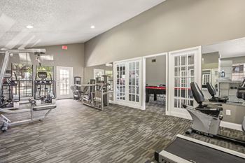 A gym with a variety of equipment including treadmills, weights, and exercise machines.